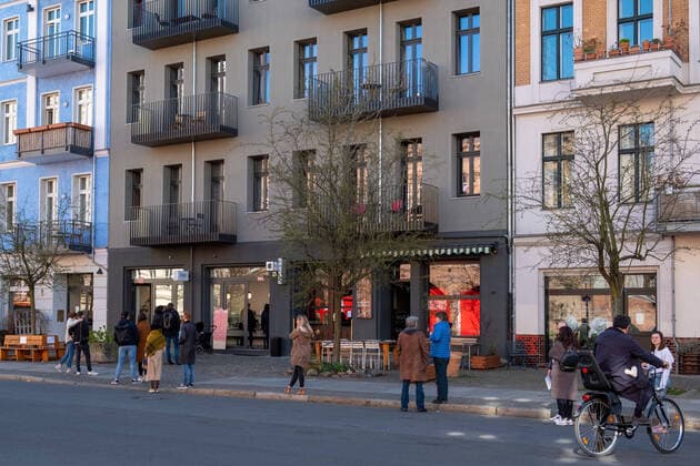 Warteschlage mit genügend Abstand zwischen den Wartenden vor einem der wenigen geöffneten Eisläden in der Oderberger Strasse in Berlin-Prenzlauer Berg Coronakrise - Anstehen mit Abstand