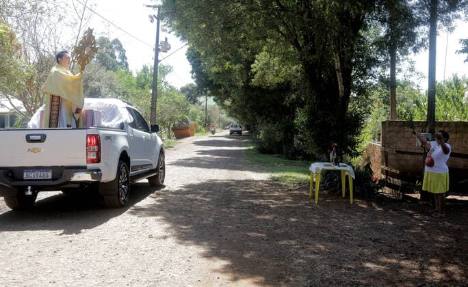 Coronavirus in Brasilien, motorisierte Prozession zum Beginn der Karwoche in Campo Mourao CAMPO MOURÃO, PR - 05.04.2020: COVID 19 ESPANTA FIES NO DOMINGO DE RAMOS - Catholics in Campo Mourão, in the Midwest Region of Paraná, celebrated Palm Sunday? beginning of Holy Week? from the gate into the residences. The faithful placed a green branch on the gates of the houses waiting for the passage of the Most Holy. Due to the recommendation of social isolation due to the Covid-19 pandemic, a disease caused by the coronavirus, a priest held a small procession blessing the homes and people of neighborhoods close to the city center. In the photo, faithful celebrate Palm Sunday from the gate of their homes. x1901699x  DirceuxPortugal