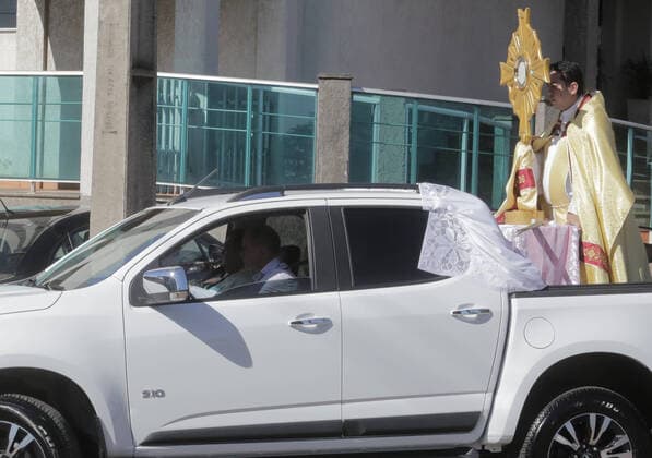 Coronavirus in Brasilien, motorisierte Prozession zum Beginn der Karwoche in Campo Mourao CAMPO MOURÃO, PR - 05.04.2020: COVID 19 ESPANTA FIES NO DOMINGO DE RAMOS - Catholics in Campo Mourão, in the Midwest Region of Paraná, celebrated Palm Sunday? beginning of Holy Week? from the gate into the residences. The faithful placed a green branch on the gates of the houses waiting for the passage of the Most Holy. Due to the recommendation of social isolation due to the Covid-19 pandemic, a disease caused by the coronavirus, a priest held a small procession blessing the homes and people of neighborhoods close to the city center. In the photo, faithful celebrate Palm Sunday from the gate of their homes. x1901710x  DirceuxPortugal
