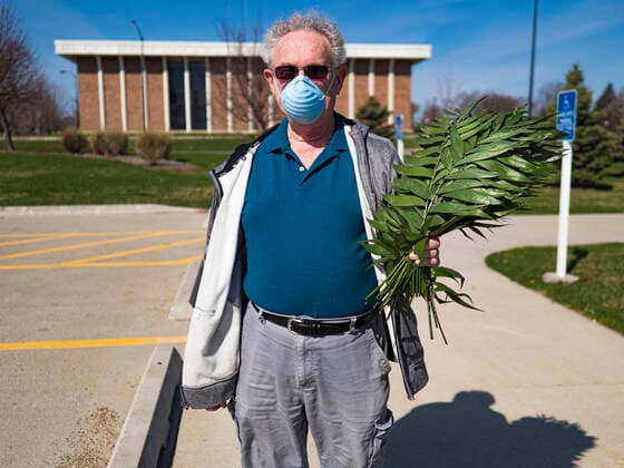 Coronavirus in den USA, Drive-Through Gottesdienst zum Auftakt der Karwoche in Des Moines, Iowa April 5, 2020, Des Moines, Iowa, U.S: A parishioner of Luther Memorial Church walks home after picking up palms at a drive through Palm Sunday service sponsored by Luther Memorial Church on the campus of Grand View University in Des Moines. About 150 people attended the service. They remained in their cars while the ministers read a short passage from the Bible, handed out palms and blessed them. On Sunday, 05 April, Iowa reported 868 confirmed cases of the Novel Coronavirus (SARS-CoV-2) and COVID-19. There have been 22 deaths attributed to COVID-19 in Iowa. Restaurants, bars, movie theaters, places that draw crowds are closed until 30 April. The Governor has not ordered shelter in place but several Mayors, including the Mayor of Des Moines, have asked residents to stay in their homes for all but essential needs. People are being enco - ZUMAk94_ 20200405_zaf_k94_025 Copyright: xJackxKurtzx