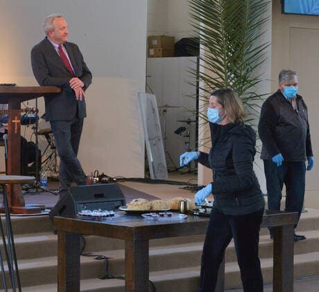 Parishioners practice social distancing guidelines as they partake in the sacrament of communion-not services to kick off Holy Week despite county and state orders restricting non-essential travel as Pastor Rob McCoy looks on (rear) at the Godspeak Calvary Chapel in the Newbury Park town of Thousand Oaks, California on Sunday, April 5, 2020. Millions of Christians around the world will spent Palm Sunday watching church service and taking communion from the comfort of their homes as they seek to abide stay-home orders intended to limit the spread of the coronavirus. File  LAP2020040521 JIMxRUYMEN