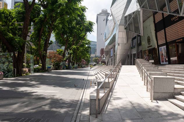 02.04.2020, Singapur, Republik Singapur, Asien - Ein Blick entlang der menschenleeren Orchard Road Einkaufsstrasse mit dem Wisma Atria Einkaufszentrum. Seit dem Ausbruch der Corona-Pandemie ist die Zahl von Menschen im oeffentlichen Leben stark zurueck gegangen. Fuer gewoehnlich ist die Orchard Road sehr belebt, momentan aber bis auf wenige Personen total verwaist.