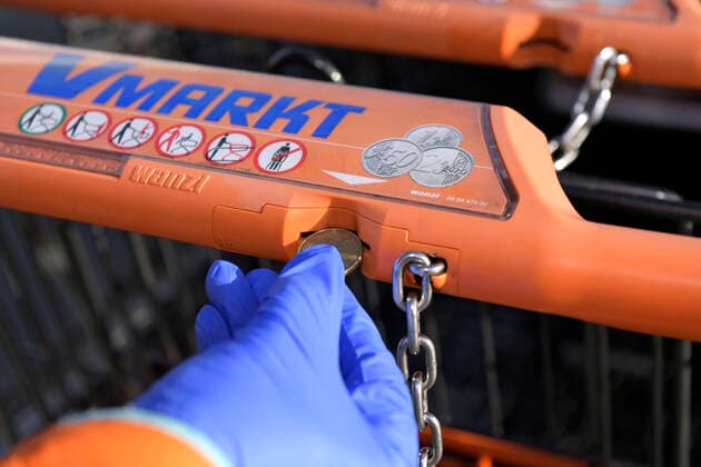06.04.2020, Hygiene am Einkaufswagen, Frau mit Gummihandschuhen steckt Münze in die Entsperrung des Einkaufswagens. 06.04.2020, Hygiene am Einkaufswagen 06.04.2020, Hygiene am Einkaufswagen