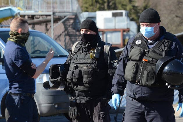 KYIV, UKRAINE - APRIL 06, 2020 - Man wearing a scarf over the lower part of his face speaks with the policemen at the Venetian walking bridge leading to the outdoor sports ground, Kyiv, capital of Ukraine. Police block entrance to Hydropark sports ground in capital  Copyright: xYevhenxKotenkox