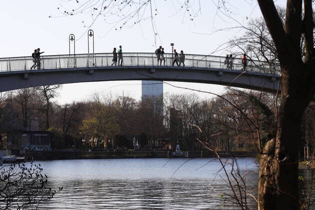 06.04.2020, Berlin - Deutschland. Im Treptower Park genießen die Leute das schöne Wetter, sie laufen über die Brücke zur Insel der Jugend. Alle beachten die Abstandsregelung während der Corona-Krise.