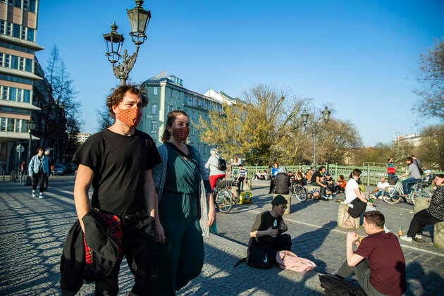 Paul und Laura tragen selbstgemachte bunte Mundschutzmasken in Berlin Kreuzberg am 6. April 2020. Um die Verbreitung des Coronavirus (SARS-CoV-2) zu verlangsamen beschlossen Bund und Laender weitere Restriktionen. Nachdem Museen, Theatern, Sportveranstaltungen usw verboten wurden sind seit einigen Tagen weitere verschaerfte Massnahmen in Kraft getreten wie z.B. Verbot von Versammlungen in der Oeffentlichkeit mit mehr als zwei Personen, Einhaltung von Mindestabstand zwischen Personen und Schliessung von Gastronomiebetrieben mit Ausnahme von Abholung und Lieferung. Coronavirus in Berlin