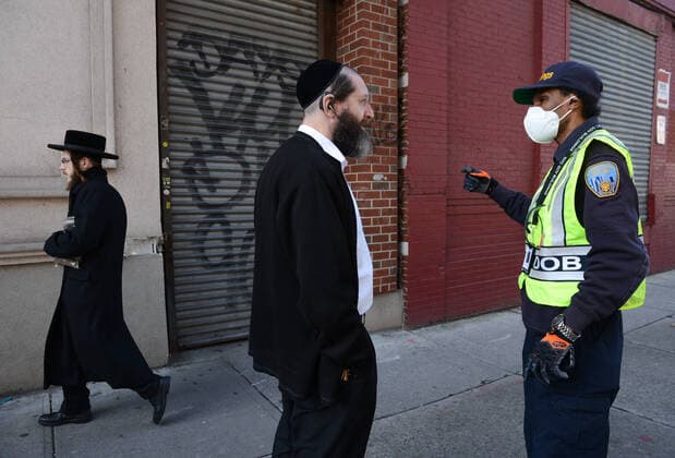 April 6, 2020, New York Brooklyn Williamsburg, USA: NYC building department officer giving a ticket to the owner of the building. Members of the Orthodox Jewish community attend the morning prayer in an illegal synagogue in a warehouse violation of the states social distancing rules. The Orthodox Jewish neighborhood which has seen an upsurge of (COVID-19) patients during the pandemic.04 06 20. New York Brooklyn Williamsburg. New York Brooklyn Williamsburg USA - ZUMAs252 20200406_znp_s252_004 Copyright: xMarcusxSantosx