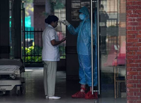 NEW DELHI, INDIA - APRIL 6: A security guard checks the temperature of a hospital staff on day thirteen of the 21-day nationwide lockdown to check the spread of coronavirus, at Moolchand Hospital, on April 6, 2020 in New Delhi, India. (Photo by Biplov Bhuyan Hindustan Times) Three Week Lockdown In India To Stop Spread Of Coronavirus COVID-19