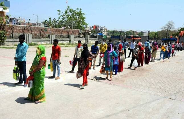 NEW DELHI, INDIA - APRIL 6: People queue while keping distance at a food distribution by the Delhi Government at a Basti Vikas Kendra, on day thirteen of the 21-day nationwide lockdown to check the spread of coronavirus at Gandhi Nagar on April 6, 2020 in New Delhi, India. (Photo by Sonu Mehta Hindustan Times) Government And NGOs Provide Food To Homeless And Poor Amid Lockdown To Prevent Covid-19
