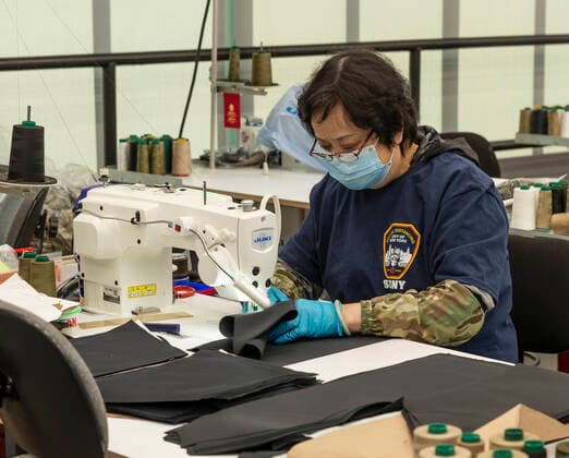 NY: Mayor de Blasio at Brooklyn Yard Worker wearing social distances t-shirt works on production line run by Crye Precision to produce protective equipment for health professionals at Brooklyn Navy Yard New York New York United States Copyright: LevxRadin