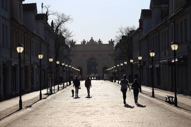 Menschen laufen am späten Nachmittag in der Brandenburger Straße, im Hintergrund das Brandenburger Tor, Potsdam, 6. April 2020. Um die Ausbreitung des Coronavirus Sars-CoV-2 zu verlangsamen gelten zur Zeit Ausgangs- und Kontaktbeschränkungen. Coronavirus Potsdam