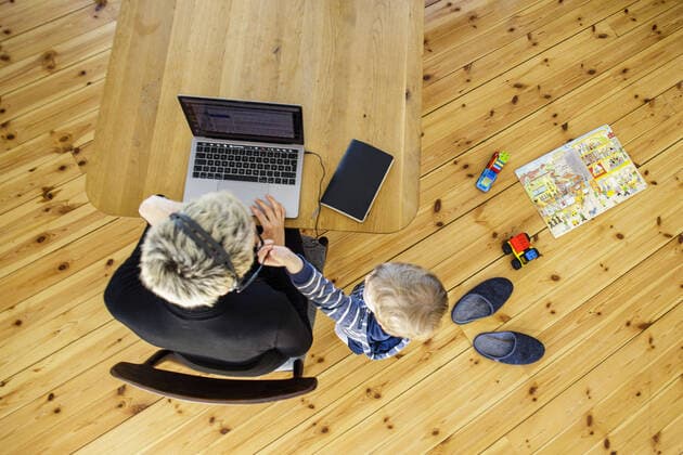 Symbolfoto zum Thema Homeoffice. Eine Frau sitzt zu Hause am Schreibtisch und arbeitet. Neben ihr spielt ein Kind. Berlin, 06.04.2020. Waehrend der Ausgangssperre und Quarantaene aufgrund des Coronavirus, COVID-19, SARS-CoV-2 sind viele Arbeitnehmer gezwungen, von zu Hause aus zu arbeiten. Eltern sind dabei doppelt belastet und muessen zusaetzlich ihre Kinder betreuen. Berlin Deutschland