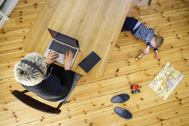 Symbolfoto zum Thema Homeoffice. Eine Frau sitzt zu Hause am Schreibtisch und arbeitet. Neben ihr spielt ein Kind. Berlin, 06.04.2020. Waehrend der Ausgangssperre und Quarantaene aufgrund des Coronavirus, COVID-19, SARS-CoV-2 sind viele Arbeitnehmer gezwungen, von zu Hause aus zu arbeiten. Eltern sind dabei doppelt belastet und muessen zusaetzlich ihre Kinder betreuen. Berlin Deutschland