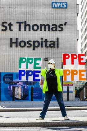 A woman holding up signs (PPE-Personal Protection Equipment) stands outside St Thomas Hospital in central London as British Prime Minister Boris Johnson is in intensive care fighting the coronavirus in London, Tuesday, April 7, 2020. (Photo Vudi Xhymshiti)  iMagoVX