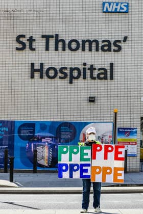 A woman holding up signs (PPE-Personal Protection Equipment) stands outside St Thomas Hospital in central London as British Prime Minister Boris Johnson is in intensive care fighting the coronavirus in London, Tuesday, April 7, 2020. (Photo Vudi Xhymshiti)  iMagoVX