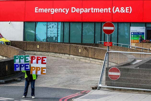A woman holding up signs (PPE-Personal Protection Equipment) stands outside St Thomas Hospital in central London as British Prime Minister Boris Johnson is in intensive care fighting the coronavirus in London, Tuesday, April 7, 2020. (Photo Vudi Xhymshiti)  iMagoVX