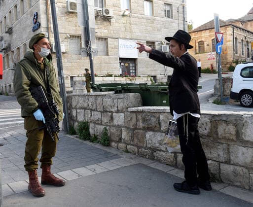 An Israeli soldier wears a mask and gloves, as protection from the coronavirus, while enforcing movement restrictions, before the Jewish holiday Passover, on Tuesday, March 7, in Jerusalem. Israeli Prime Minister Benjamin announced severe travel restrictions and a curfew for the Passover holiday, as an effort to halt the spread of the coronavirus.  JER2020040713 DEBBIExHILL