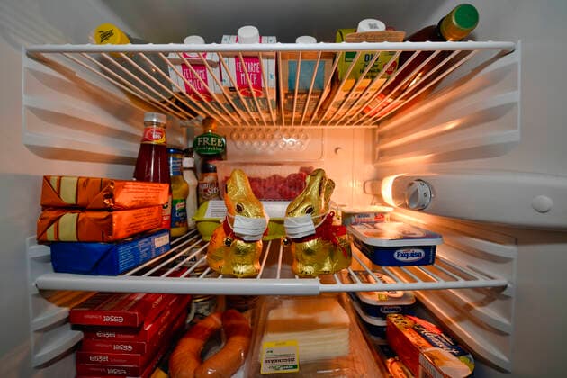 Zwei Schoko-Osterhasen mit Mundschutz, gefüllter Kühlschrank während Quarantäne, häusliche Isolation, Ausgangssperre wegen Coronavirus, Sars-CoV-2. Covid-19, Stuttgart, Baden-Württemberg, Deutschland Kühlschrank prall gefüllt
