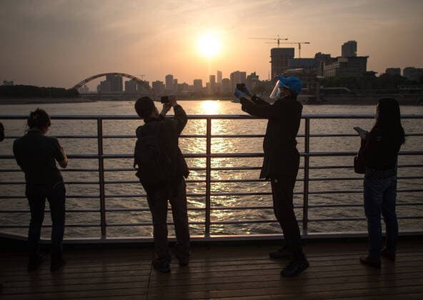 (200408) -- WUHAN, April 8, 2020 -- Passengers watch the view of sunset on the ferry in Wuhan, central China s Hubei Province, April 8, 2020. Wuhan restored its operation of ferries from Wednesday, with the Wuhan Yangtze River ferry company having reopened its two ship routes. Wuhan, the megacity in central China, lifted outbound travel restrictions from Wednesday after almost 11 weeks of lockdown to stem the spread of COVID-19. ) CHINA-HUBEI-WUHAN-FERRY-RESTORATION (CN) XiaoxYijiu 