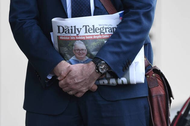 GLADYS BEREJIKLIAN CORONAVIRUS PRESSER, A media adviser holds a newspaper cover featuring NSW Minister for the Arts Don Harwin as NSW Premier Gladys Berejiklian speaks to the media during a press conference in Sydney, Thursday, April 9, 2020. NSW has recorded its lowest daily rise in coronavirus cases in more than three weeks as detectives seize evidence from the ill-fated Ruby Princess cruise ship. ( NO ARCHIVING, EDITORIAL USE ONLY, NO USE IN BOOKS WITHOUT CONSENT SYDNEY NSW AUSTRALIA  Copyright: xJOELxCARRETTx 20200409001462530125
