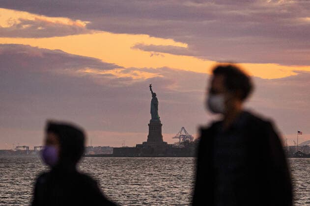 200408 People wear protective face masks when walking in Wagner Park in front of The Statue of Liberty as the coronavirus, COVID-19, outbreak continues on April 8, 2020 in New York, NY, USA. Across the city businesses, schools and places of work have been shutting down, leading to empty streets and quiet neighborhoods. Photo: Joel Marklund BILDBYRAN kod JM 88132 bbeng coronavirus covid-19 virus corona sjukdom Frihetsgudinnan Copyright: JOELxMARKLUND 47124520st