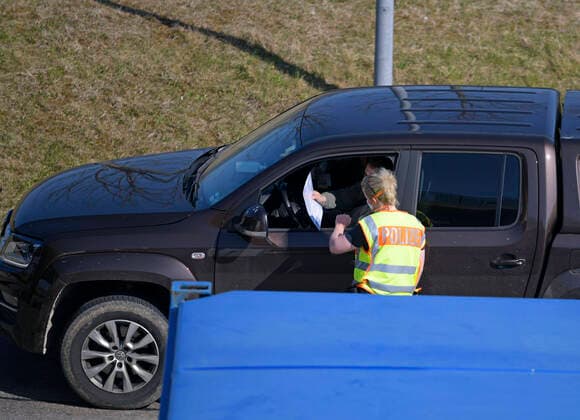 09.04.2020, Füssen im Allgäu, Negative Auswirkungen wegen Corona-Virus-Pandemie, Autobahn A7 Richtung Österreich Grenztunnel Füssen-Reutte ist leer, die Fahrbahn aus Österreich ist einspurig gesperrt, die Polizei leitet den Verkehr zur Einreiskontrolle jedes Fahrzeuges in die Ausfahrt hinaus. Polizeibeamtin prüft die Papiere eines Autofahrers aus Österreich. 09.04.2020, Auswirkungen Tourismus wegen Corona-Virus 09.04.2020, Auswirkungen Tourismus wegen Corona-Virus