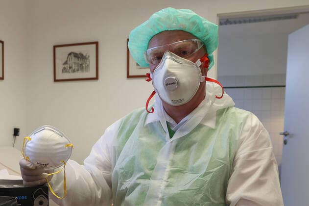 Coronavirus, Maskenmangel in deutschen Arztpraxen, Arzt, Arztpraxis, Hausarzt, Arzt mit Mundschutz, FFP2-Maske , Atemschutzmaske mit Filter, und Einmalschutzkittel, Schutzbrille,
