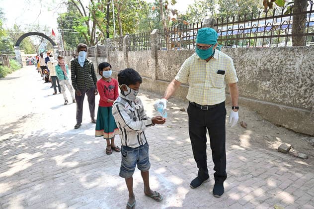 April 9, 2020, Prayagraj, Uttar Pradesh, India: Social worker spray sanitiser on beneficiaries hand as People queue to get free food at a government school during a government-imposed nationwide lockdown as a preventive measure against the spread of the COVID-19 coronavirus in Prayagraj on Thursday. Prayagraj India - ZUMAv115 20200409_zap_v115_015 Copyright: xPrabhatxKumarxVermax