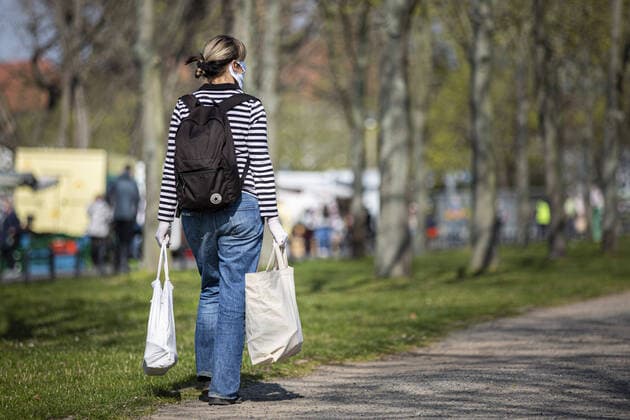Eine Frau mit Mundschutz und Schutzhandschuhen traegt zwei Beutel auf dem Wochenmarkt an der Lingnerallee in Dresden, 09.04.2020. Aufgrund der Verbreitung des Coronaviruses gibt es erstmals eine Maskenpflicht auf einem Wochenmarkt in Dresden. Dresden Deutschland