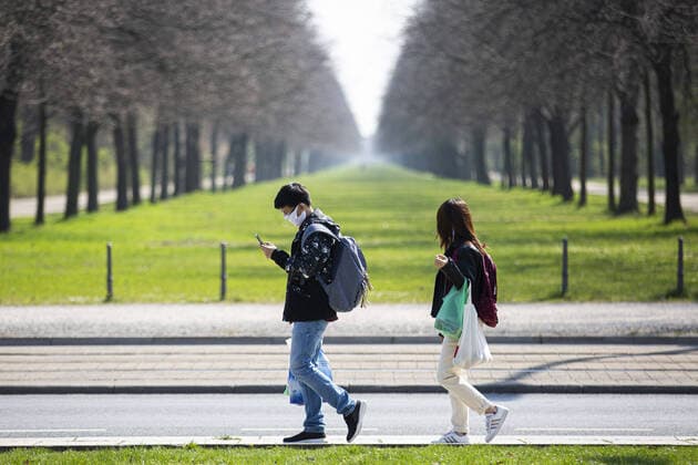 Ein Mann und eine Frau mit Mundschutz laufen entlang des Grossen Gartens in Dresden, 09.04.2020. Aufgrund der Verbreitung des Coronaviruses gibt es deutschlandweit Ausgangsbeschraenkungen. Dresden Deutschland