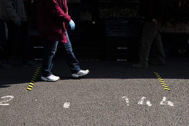 Eine Frau mit Schutzhandschuhen laeuft zwischen zwei Abstandsmarkierungen auf dem Wochenmarkt an der Lingnerallee in Dresden, 09.04.2020. Aufgrund der Verbreitung des Coronaviruses gibt es erstmals eine Maskenpflicht auf einem Wochenmarkt in Dresden. Dresden Deutschland