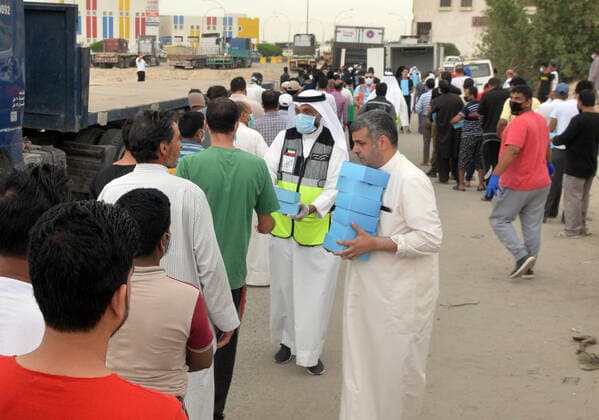 (200409) -- FARWANIYA GOVERNORATE (KUWAIT), April 9, 2020 (Xinhua) -- Workers distribute food to residents in the area of Jleeb Al-Shuyoukh in Farwaniya Governorate, Kuwait, on April 9, 2020. Kuwaiti government distributed on Thursday food baskets to residents of areas of Mahboula and Jleeb Al-Shuyoukh which are under lockdown to curb the spread of COVID-19. Kuwait reported on Thursday 55 new COVID-19 cases, bringing the total number in the country to 910, the health ministry said in a statement. (Photo by Asad Xinhua) KUWAIT-FARWANIYA GOVERNORATE-COVID-19-FOOD DISTRIBUTION 