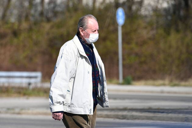 Oeffentliches Leben in Zeiten der Coronavirus Pandemie am 05.04.2020 in Muenchen. Ein alter Mann geht mit Gesichtsmaske,Schutzmaske,Mundschutz ueber eine Strasse. Ausgangsbeschraenkungen,Kontaktsperre.