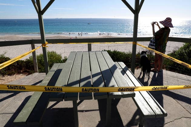GOOD FRIDAY COVID-19, A lady with her dog takes a picture of Mosman Beach next to a taped off picnic bench in Perth on Friday, April 10, 2020. Beaches remain open but the Western Australian government have warned the public they could be closed if people do not adhere to social distancing rules. ( NO ARCHIVING, EDITORIAL USE ONLY, NO USE IN BOOKS WITHOUT CONSENT PERTH WA AUSTRALIA  Copyright: xRICHARDxWAINWRIGHTx 20200410001462837527