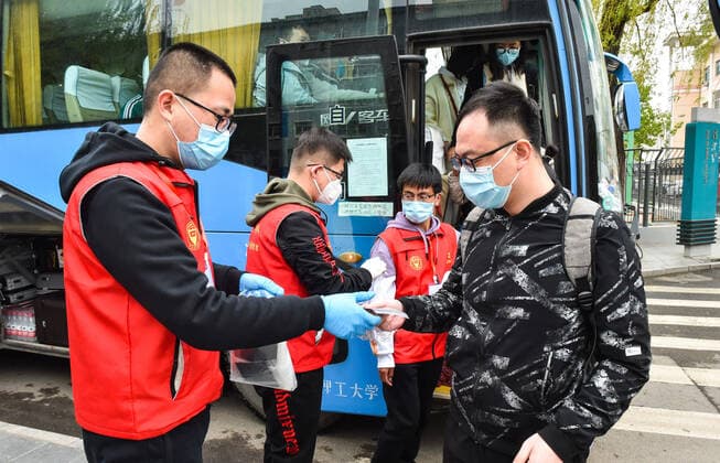 (200410) -- TAIYUAN, April 10, 2020 -- Volunteers distribute face masks to students of Taiyuan University of Technology at the entrance of the school in Taiyuan, north China s Shanxi Province, April 10, 2020. The first batch of graduating students and post-graduates and doctorial students with research tasks in Shanxi resumed classes from Friday. ) CHINA-SHANXI-UNIVERSITY-CLASS-RESUMPTION (CN) ChaixTing 