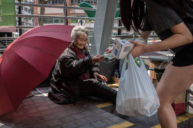 April 10, 2020, Hong Kong, China: An elderly homeless woman receives a surgical mask from a volunteer as a preventive measure against the spread of Coronavirus..As the coronavirus pandemic worsens, thousands of Hong Kong residents who live in cramped coffin homes or homeless situation are struggling to adjust to their new reality. Coronavirus cases in Hong Kong are close to the 1,000 mark. Hong Kong China - ZUMAs197 20200410_zaa_s197_018 Copyright: xSOPAxImagesx