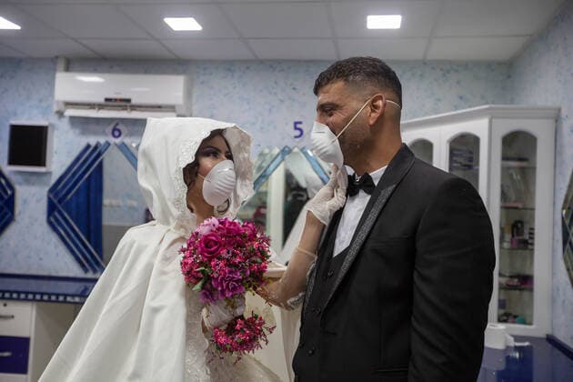 (200410) -- BETHLEHEM, April 10, 2020 (Xinhua) -- Palestinian bride, Shima al-Titi, adjusts the face mask for her groom, Ishaq Musleh, before they leave the beauty salon in the Palestinian Deheisheh refugee camp near the West Bank city of Bethlehem, on April 10, 2020. Wearing masks and gloves as preventive measures, the couple celebrated their wedding during the COVID-19 outbreak. (Photo by Luay Sababa Xinhua) MIDEAST-BETHLEHEM-COVID-19-WEDDING 