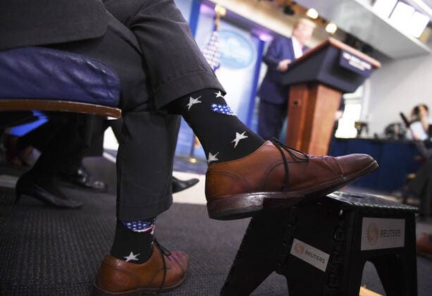 Dr. Anthony Fauci, director of the National Institute of Allergy and Infectious Diseases, wears star spangled socks as he listens to President Donald Trump speak at a Coronavirus briefing at the White House on Friday, April 10, 2020, in Washington, DC. With the U.S. death toll from the coronavirus pandemic expected to peak over the weekend, most of the country will be firmly under stay-at-home orders on Easter Sunday.  WAS202041050513 KEVINxDIETSCH