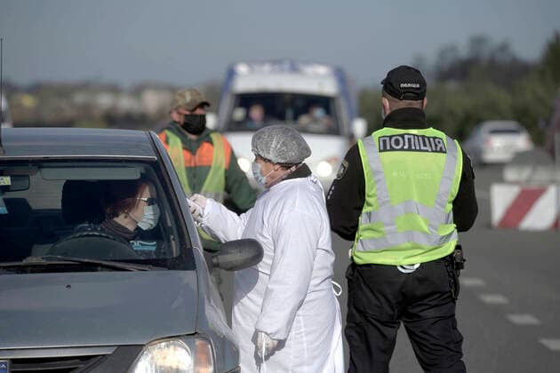 ZOLOCHIV, UKRAINE - APRIL 10, 2020 - A healthcare worker accompanied by a police officer measures the body temperature of a driver at a roadblock set up on the border with Ternopil Region during the COVID-19 outbreak, Zolochiv, Lviv Region, western Ukraine. Roadblock in Zolochiv  Copyright: xMARKIIANxLYSEIKOx
