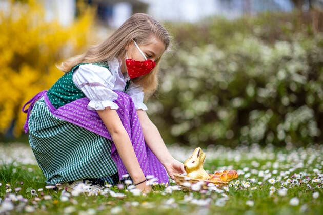 Graz THEMENBILD - Ein Maedchen in Trachtund mit NMS-Maske mit einem Osternest und Schokolade-Hasen auf einer Blumenwiese, aufgenommen am 10. April 2020, in Graz a girl in traditional austrian dress and a face mask is seeking for a easter present in a flower meadow on 10 April 2020.