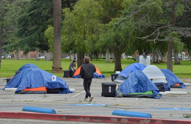A veteran walks amongst homeless tents in a parking lot at the West Los Angeles VA Medical Center during the coronavirus pandemic in Los Angeles on Friday, April 10, 2020.  LAP2020041011 JIMxRUYMEN
