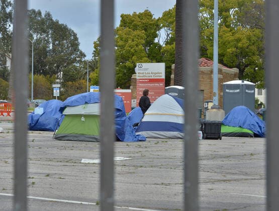 A veteran walks amongst homeless tents in a parking lot at the West Los Angeles VA Medical Center during the coronavirus pandemic in Los Angeles on Friday, April 10, 2020.  LAP2020041017 JIMxRUYMEN