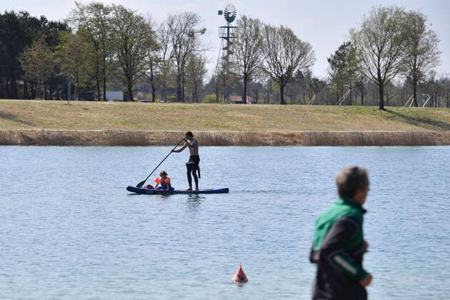 Ostern in Zeiten der Corona Pandemie- oeffentliches Leben am 11.04.2020 am Buga See im Riemer Park. Ein Vater paddelt zusammen mit seinem Kind, das vor ihm auf dem Board sitzt ueber den See. Stand Up Paddling.Stand Up Paddler. Das fruehlingshafte Wetter treibt die Bevoelkerung an die frische Luft,immer mit dem noetigen Abstand wegen einer Ansteckung mit dem Coronavirus. Ausgangsbeschraenkungen,Kontaktsperre.