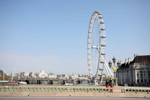 Day Nineteen of Lockdown in London. A couple on Westminster Bridge, nwith the London Eye behind, in London on Easter Saturday. It is the first public holiday of the year, and many people enjoy the long weekend by going out and about or on holiday, but this year the country is on lockdown due to the COVID-19 Coronavirus pandemic. People are not allowed to leave home except for minimal food shopping, medical treatment, exercise - once a day, and essential work. COVID-19 Coronavirus lockdown, London, UK, on April 11, 2020