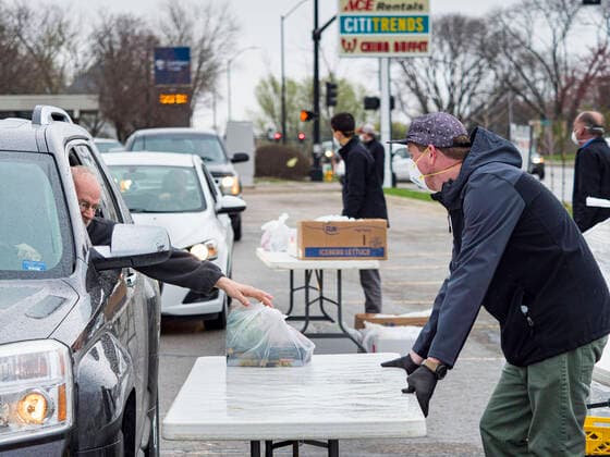 April 11, 2020, Des Moines, Iowa, U.S: JORDON ELWELL, owner and CEO of Midwest Foods, uses a plastic table to pass a ready to cook pasta meal to a motorist during a food distribution in Des Moines. Most non-essential businesses in Iowa are closed until 30 April. Because of business closings causes by the Novel Coronavirus (SARS-CoV-2) pandemic, well over 100,000 Iowans filed first time claims for unemployment in the last three weeks, more than applied during the peak of the Great Recession of 2008. Local food banks have seen an unprecedented spike in people seeking nutritional assistance. Midwest Foods, a Des Moines based company and owner of Ginos Fine Italian Foods, gave away 1,000 complete dinners with sauce, noodles, salad, and dressing Saturday morning. People started lining up 3 hours before the food distribution began. The food dis - ZUMAk94_ 20200411_zaf_k94_001 Copyright: xJackxKurtzx