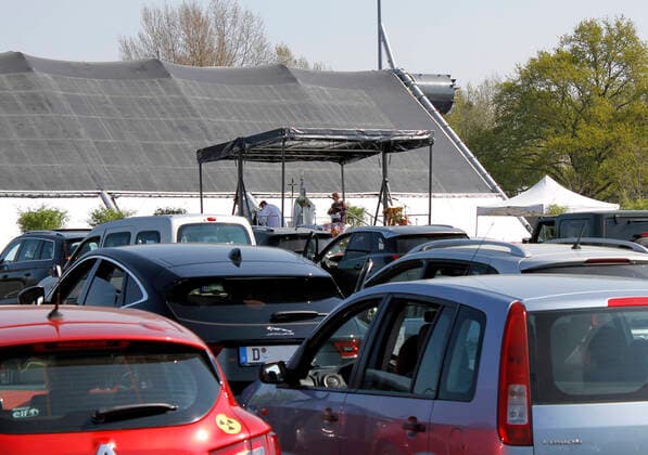 12.04.2020, Katholische Ostermesse im Autokino Düsseldorf, der Gottesdienst auf einer Bühne vor der heruntergeklappten Leinwand, davor Zuschauende in ihren Autos. 12.04.2020, Katholische Ostermesse im Autokino Düsseldorf 12.04.2020, Katholische Ostermesse im Autokino Düsseldorf