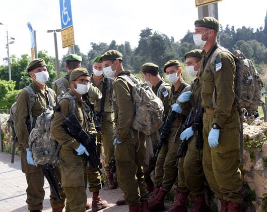 Israeli soldiers wear masks and gloves, as protection against the coronavirus, before being deployed to lockdown religious neighborhoods in Jerusalem, on Sunday, April 12, 2020. The Israeli government deployed a 1,000 police to enforce a full closure on Jewish religious neighborhoods with the highest rate of coronavirus in Jerusalem. According to the Health Ministry about 75 percent of the infected in Jerusalem live in the Ultra-Orthodox neighborhoods.  JER2020041220 DEBBIExHILL