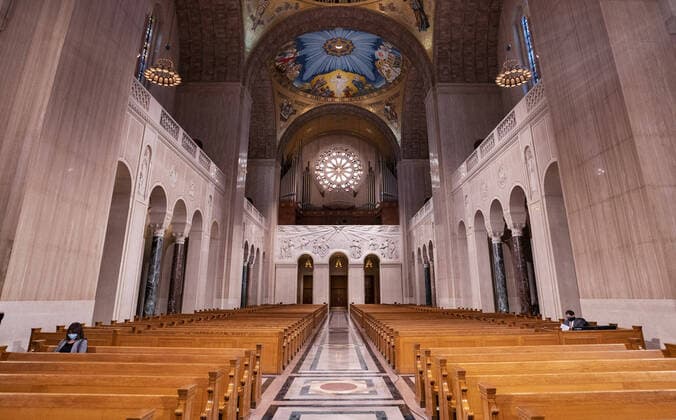 A woman wears as mask as she sits in a pew prior to a live-stream Easter mass at the Basilica of the National Shrine of the Immaculate Conception, in Washington, DC, Sunday, April 12, 2020. The Archdiocese of Washington DC closed the Basilica to the public and live-streamed the mass due to the coronavirus COVID-19 pandemic.  WAP20200412301 KEVINxDIETSCH