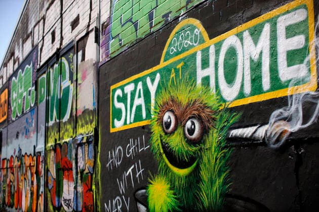 Duesseldorf, Deutschland, 12.04.2020 Das Graffiti Wandbild an der Aussenwand einer Lagerhalle in Duesseldorf - Moersenbroich verwendet den Slogan zuhause zu bleiben ( Stay at Home ) mit der gleichzeitigen Empfehlung dort mit einem Joint zu entspannen ( Chill with Mary Jane )