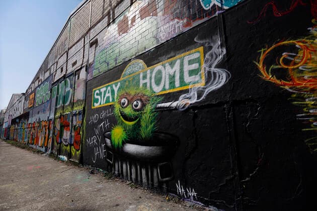 Duesseldorf, Deutschland, 12.04.2020 Das Graffiti Wandbild an der Aussenwand einer Lagerhalle in Duesseldorf - Moersenbroich verwendet den Slogan zuhause zu bleiben ( Stay at Home ) mit der gleichzeitigen Empfehlung dort mit einem Joint zu entspannen ( Chill with Mary Jane )